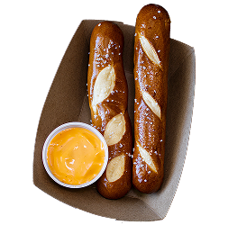 Pretzel sticks with cheese dip in tray.